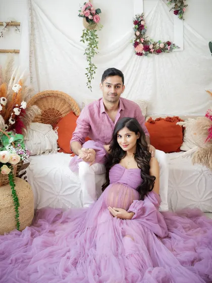 A fairytale moment for the expecting couple. The mom-to-be's flowing lavender gown and her partner's gentle hold create a romantic and dreamy scene.