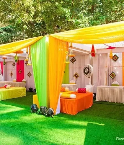 I bring energy to your Mehendi ceremony with vibrant outdoor setups. This decor uses a bright color palette of yellow, green, and orange drapes, with comfortable low diwan seating and festive hangings for a fun, celebratory vibe.