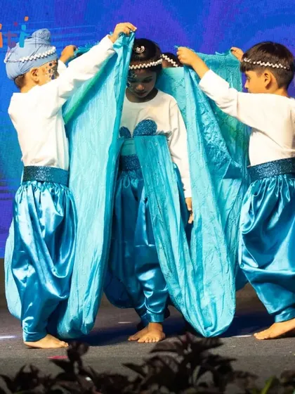 Performers use a large blue cloth to create the illusion of a wave, showcasing their teamwork and creativity.