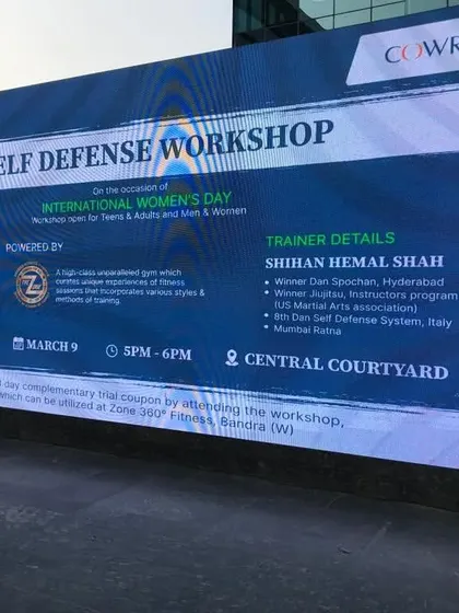 The event banner for our Self Defense Workshop at a corporate park, displayed on a large screen for International Women's Day.