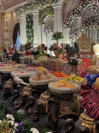 A close-up of the offering table in front of the classical pillar stage, with a focus on the dolls and props.