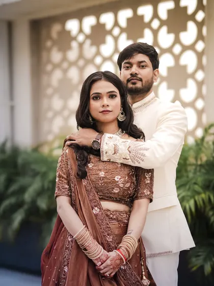 A classic portrait of the engaged couple. The groom's hand on the bride's shoulder creates a sense of intimacy and connection, set against a modern architectural backdrop.