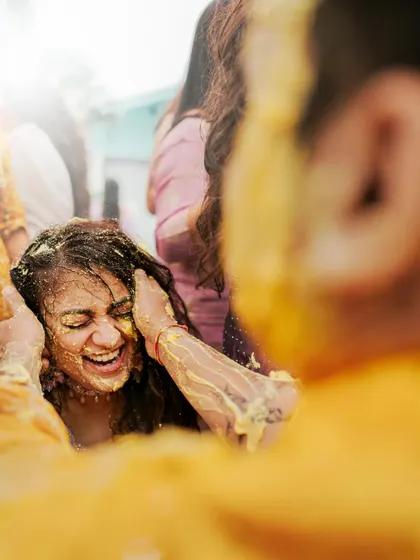A close-up of the bride laughing as Haldi is applied to her. This candid shot captures a moment of pure, unscripted joy.