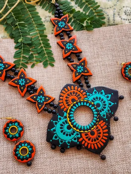 The butterfly-shaped pendant necklace in a striking black, orange, and sea green combination.
