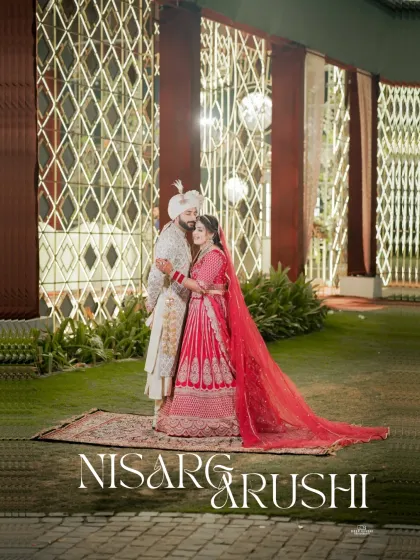 A full-length portrait of the couple against a beautifully lit backdrop. The bride's long red veil and their elegant pose make for a regal photograph.