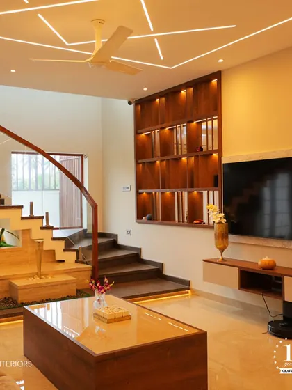 This elegant living room features a stunning double-height display unit next to a curved staircase. The warm wood tones and integrated lighting create a sophisticated yet welcoming atmosphere, showcasing our signature style.