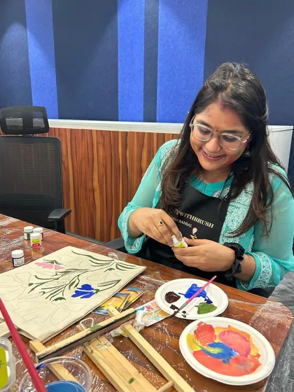 It's all in the details! A painter carefully chooses her colors for a beautiful floral design on a tote bag.