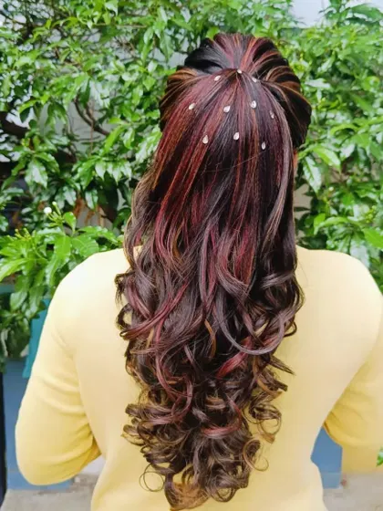 A high ponytail with dramatic curls on colored hair, showing a fun and stylish look for a reception.