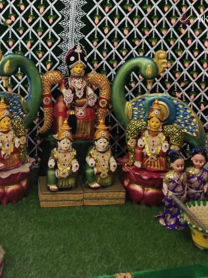 A close-up of the traditional 'Pattada Gombe' arrangement for a baby shower. The dolls are dressed in festive attire and placed amidst peacock figures, representing prosperity and joy.