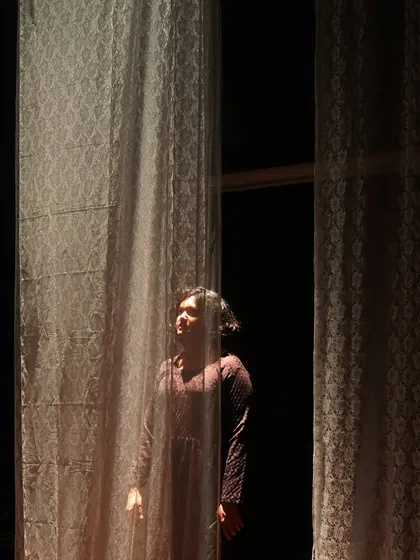 A daughter yearns for the outside world in "The House of Bernarda Alba." The set and lighting design create a feeling of confinement, with light representing a hope for freedom.