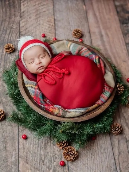 An overhead shot of a baby nestled in a Christmas wreath. I use props like pinecones and berries to create a classic holiday feel.