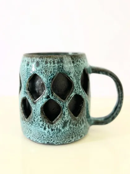 A different angle of the double-walled mug with a geometric pattern, showing the depth created by the carving.