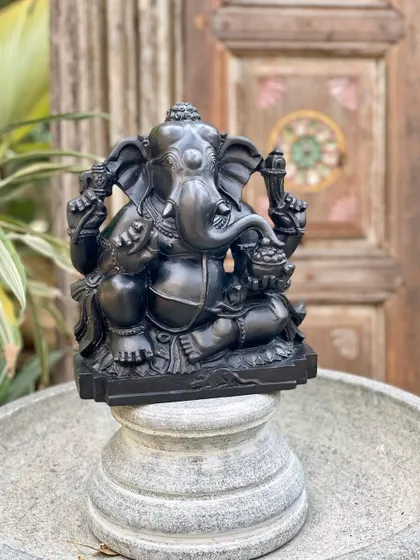 Our Ganesha statue, carved from dark Krishna shila stone, is displayed on a granite plinth, highlighting its exquisite, handcrafted details.