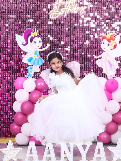 A fairy-themed 8th birthday party fit for a princess. The decor features a sparkling pink sequin wall, whimsical fairy cutouts, and a large light-up number '8' to make the birthday girl feel extra special.