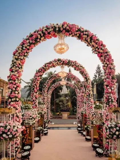 This magnificent entrance features grand arches completely covered in pink and white roses, with crystal chandeliers hanging within each arch. It’s a design that promises a fairytale wedding from the very first moment.