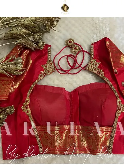 A simple and elegant red blouse with minimal buti embroidery. The back features a beautiful cutout design framed with a delicate line of zardosi work.