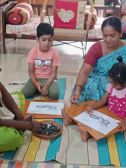 An adult helps a young child with a coloring sheet of an ant, making the activity accessible for all ages.