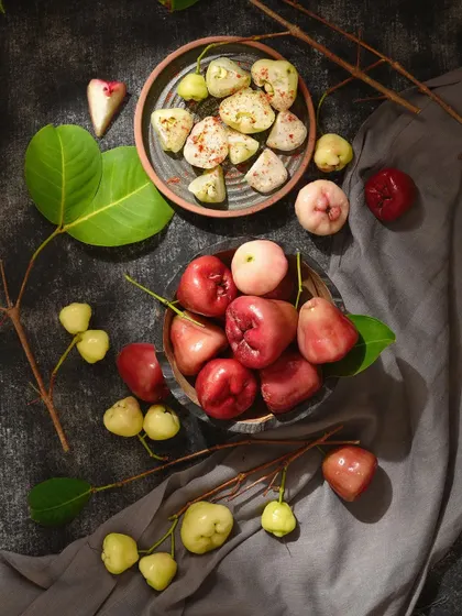I love playing with color and composition in food photography. This image contrasts the different colors of water apples against a dark background, with some sliced to show their texture with masala.