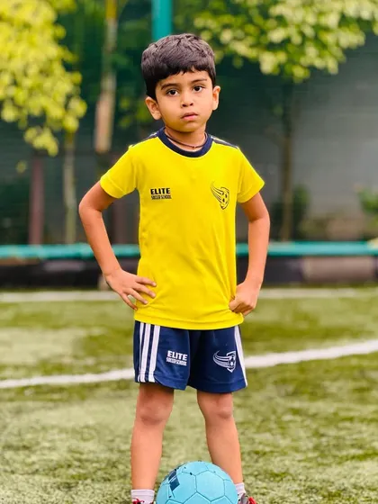 A young player posing confidently with his football.