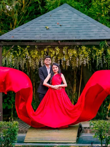 The flowing red gown creates a beautiful, wavy shape in this shot at the gazebo. It's a dynamic and artistic take on the classic couple portrait.