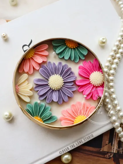 This Daisy Urli showcases a cooler, pastel color scheme with purple, teal, and pink flowers. The attention to detail in each petal really makes these candles stand out as decorative art.