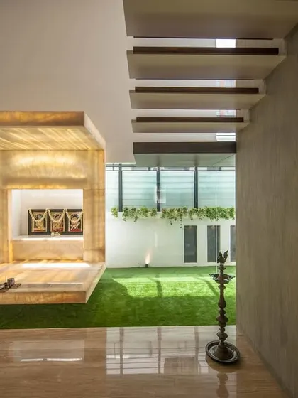 Another perspective of the backlit onyx pooja room, showing how it anchors the space next to the floating staircase.