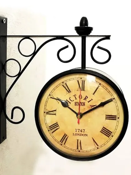 This vintage-style station clock in black offers a strong contrast against a light-colored wall.