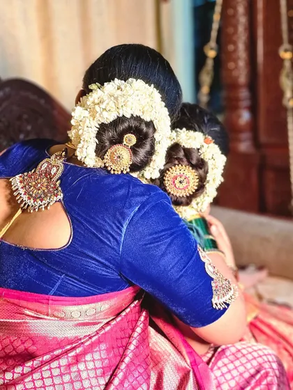 A back view of the matching mother-daughter hairstyles, showcasing the intricate buns and beautiful floral decorations. A heartwarming display of tradition.