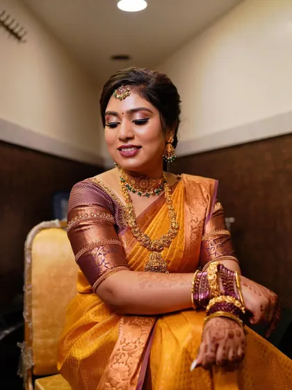A seated portrait that highlights the rich color of the saree and the intricate jewelry.