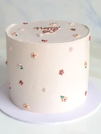 A tall, elegant cake in a neutral tone, decorated with tiny, hand-piped flowers. This minimalist design is perfect for a sophisticated 60th birthday celebration.
