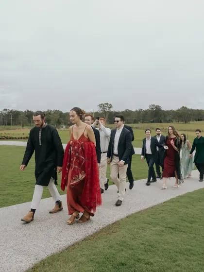 Guests walking through the beautiful green landscape of the Australian countryside for Manchal and Luca's wedding. It's a candid moment that captures the journey of the day.