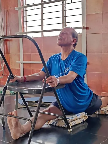 Here I am in Hanumanasana, supported by a chair and blankets. This is an example of how we adapt poses for online practice, focusing on opening the body intelligently.