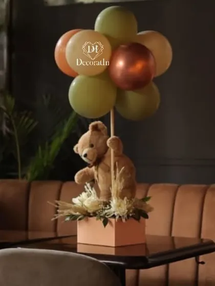 An adorable teddy bear centerpiece, with the bear holding a bunch of balloons, perfect for guest tables.