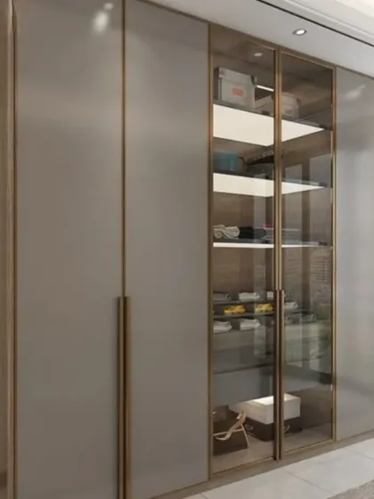 A wide wardrobe unit with a mix of solid and glass doors, framed in a subtle gold trim for a sophisticated and luxurious appearance.
