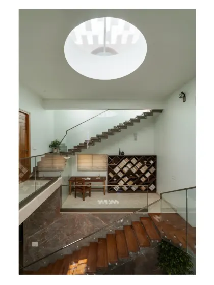 A library and study nook are cleverly tucked into the mezzanine level of a double-height space, crowned by a circular skylight that brings in natural light.