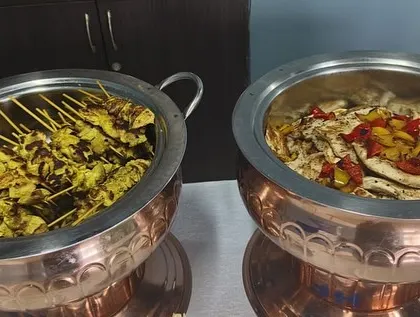We offer a diverse menu that goes beyond Indian cuisine. This image features our popular appetizers: chicken satay with a peanut marinade and a light grilled chicken and bell pepper salad.
