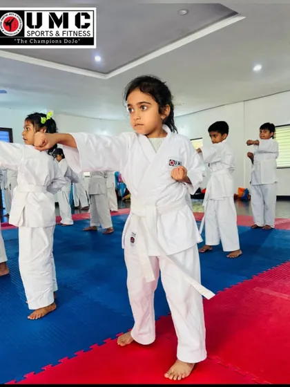 A young girl in her white belt gi practices a focused punch. We welcome beginners of all ages and help them build a strong foundation.