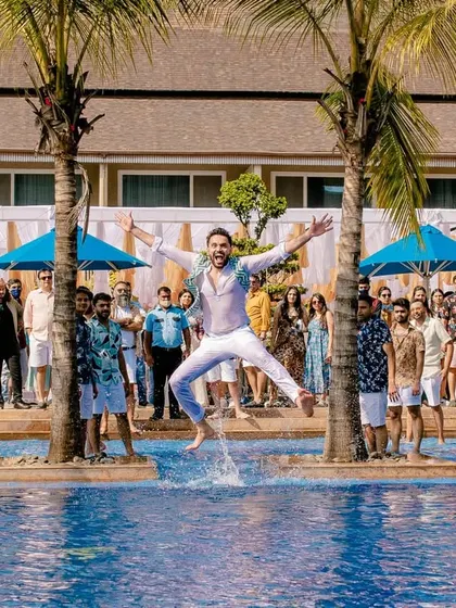 The groom making a splash with a jump into the pool, kicking off the pool party aspect of the celebration.