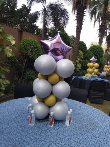 A stylish balloon centerpiece for a cocktail table. The combination of silver, gold, and a purple star foil balloon adds a touch of glamour to an outdoor event.