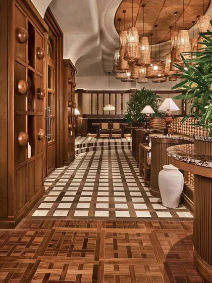 The interplay of materials at One8 Commune, with intricately carved wooden railings, patterned flooring, and a cluster of rattan pendant lights. This detail shot highlights the craftsmanship and tactile richness of the restaurant's interior design.