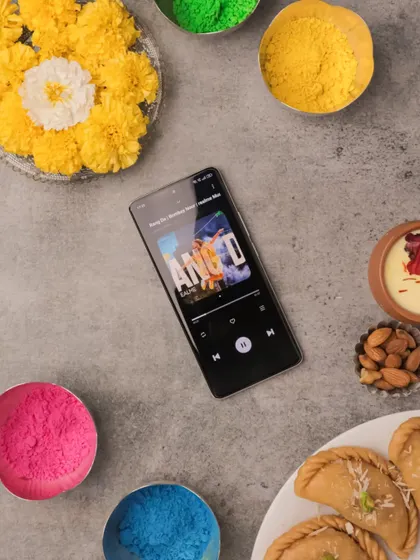 A colorful flatlay for the festival of Holi. I arranged the realme 10 Pro+ 5G among bowls of colored powder, flowers, and traditional sweets to capture the vibrant spirit of the occasion.