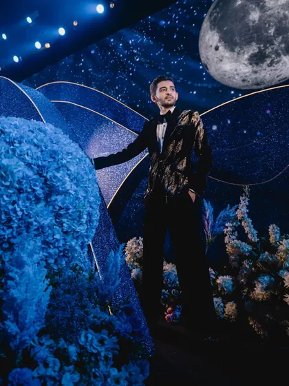 The groom is pictured against the celestial backdrop, with a large, realistic moon model hanging in the sky, adding to the authenticity of our created universe.