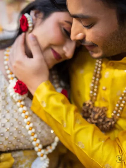 An intimate close-up of the groom gently holding the bride's face during their Haldi, a tender moment filled with love.