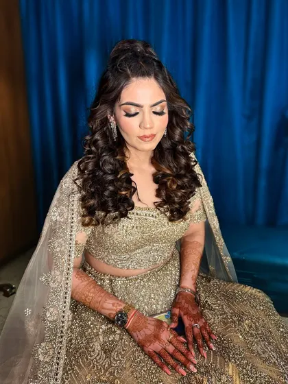 A full view of this Sangeet bride's look. The golden lehenga is paired with a soft smokey eye and a voluminous half-up hairstyle.