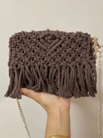 Holding my brown macrame sling bag. It's lightweight but sturdy, and the gold chain adds a really nice touch of elegance.