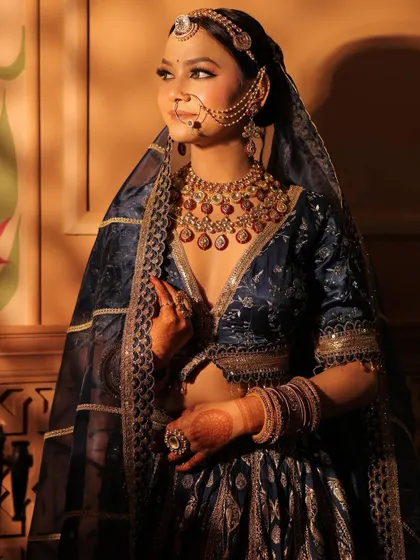 A close-up on the bride, showcasing the heavy, traditional jewellery paired with the royal blue Banarasi lehenga.