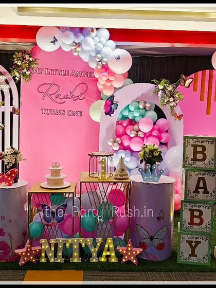 Nitya's first birthday was a vibrant butterfly land. The hot pink and teal color scheme, combined with large butterfly wings and a light-up number "1", created a bold and beautiful celebration.