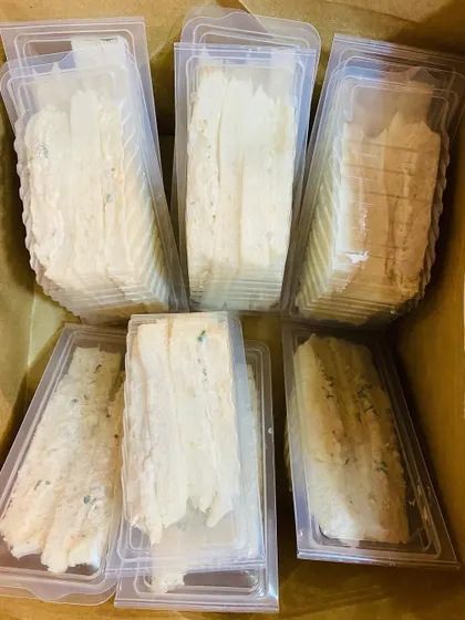A large order of chicken mayo sandwiches, packed and ready to go inside a delivery bag.