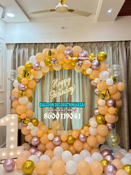 An elegant first birthday ring decoration. This full balloon ring in pastel peach, white, and chrome gold is paired with a large marquee number '1' for a classic look.