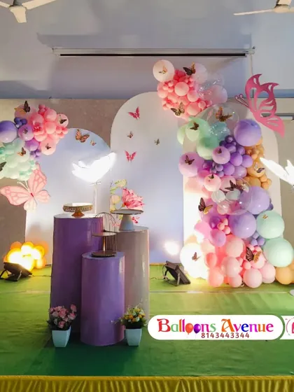 A wider view of the butterfly garden setup on a stage, showing the arrangement of pedestals and props.